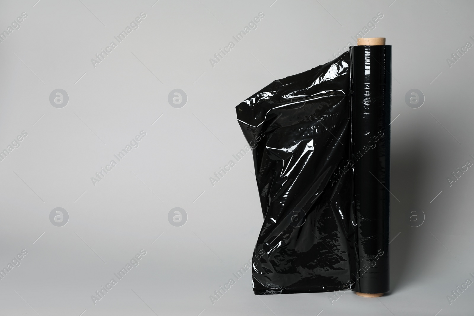 Photo of Roll of black stretch wrap on light grey background. Space for text