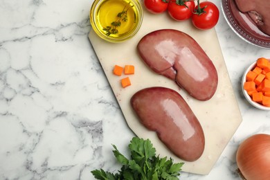 Photo of Fresh raw pork kidneys and ingredients on white marble table, flat lay. Space for text