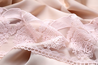 Photo of Beautiful lace on beige fabric, closeup view