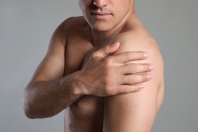 Photo of Man suffering from shoulder pain on beige background, closeup