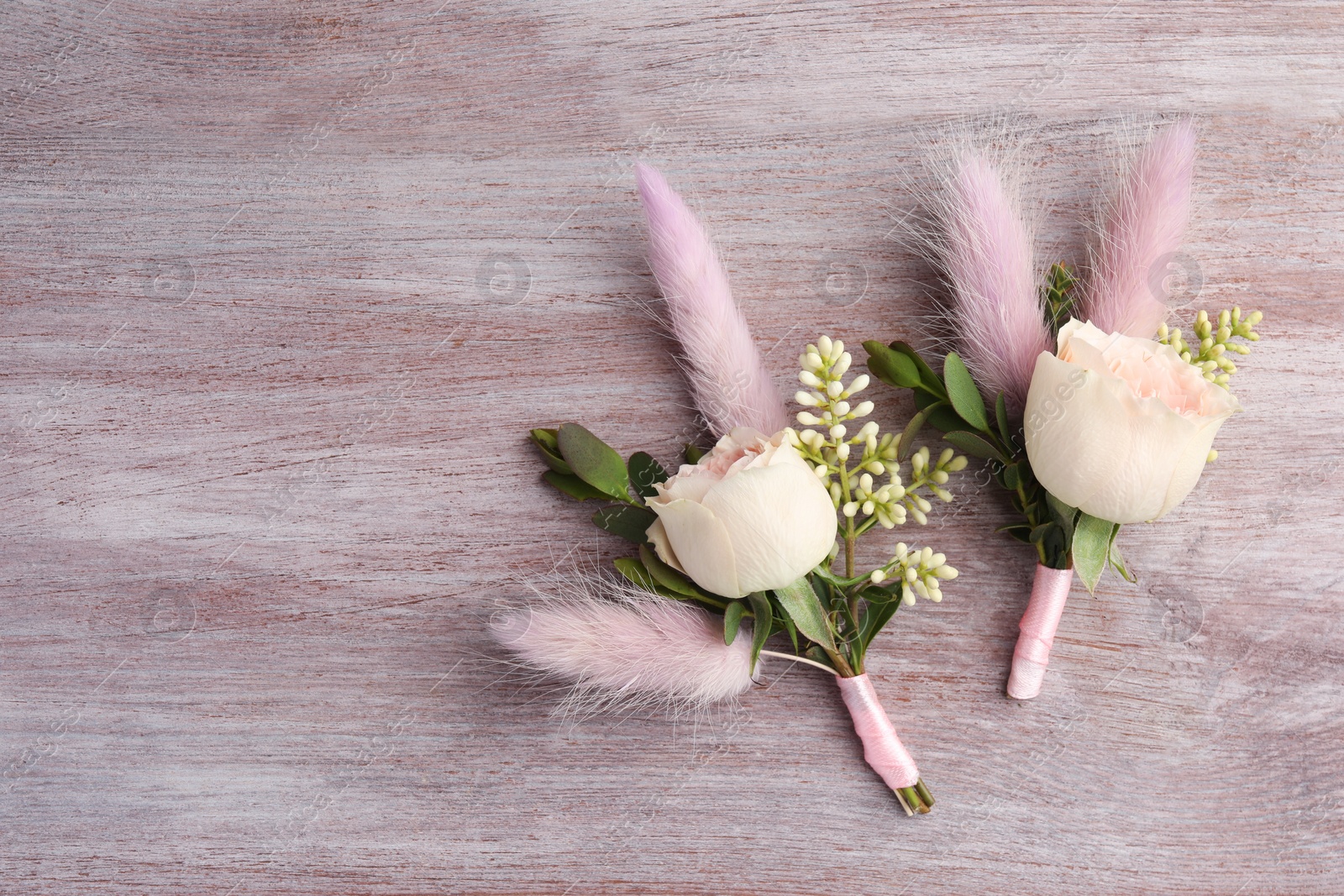 Photo of Small stylish boutonnieres on light wooden table, top view. Space for text