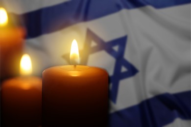 Image of Burning candles against flag of Israel, closeup