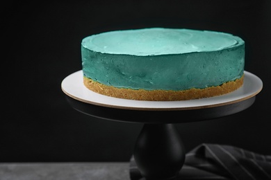 Photo of Delicious homemade spirulina cheesecake on table against black background