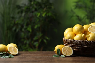 Photo of Fresh lemons in wicker basket on wooden table. Space for text