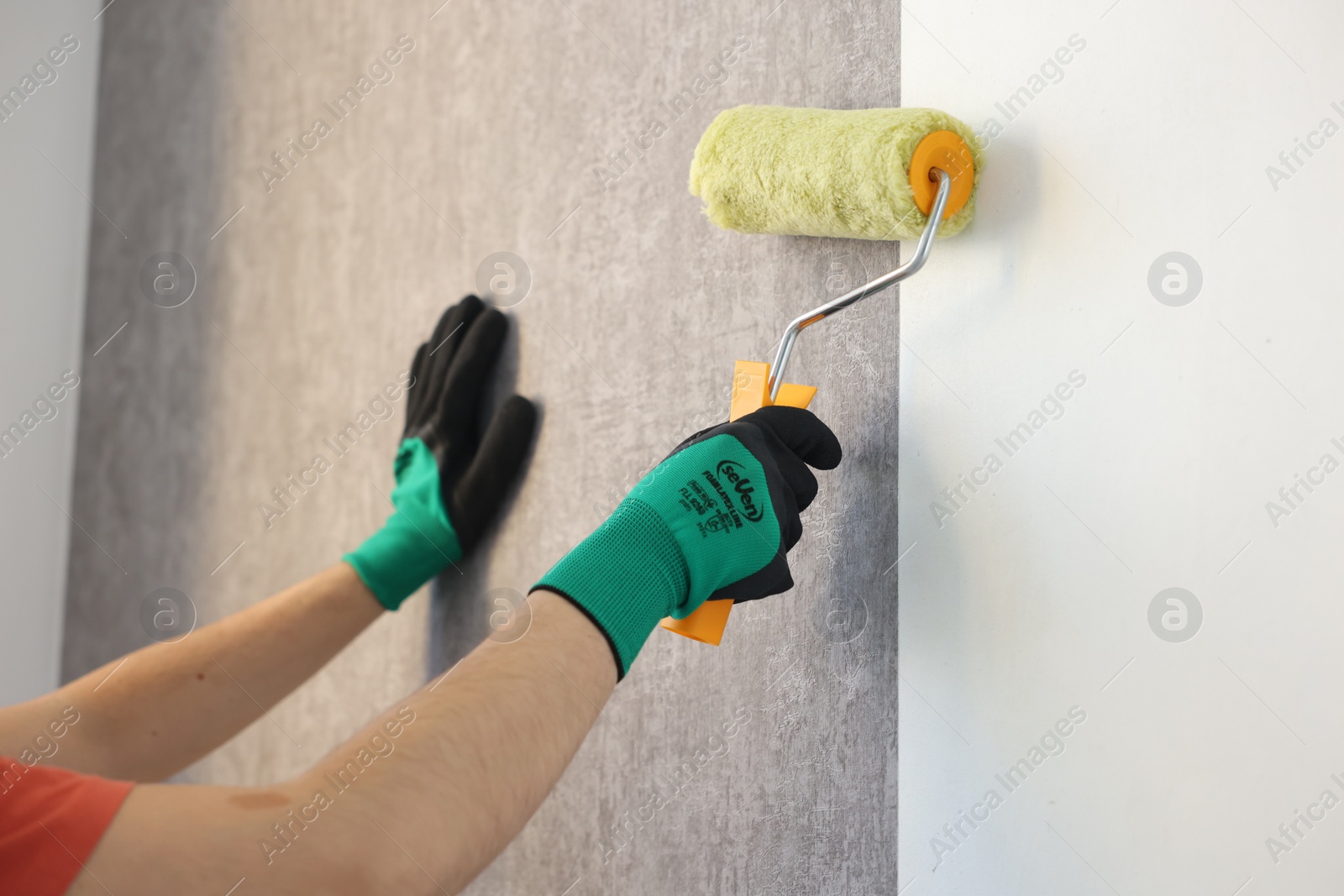 Photo of Man hanging stylish gray wallpaper in room