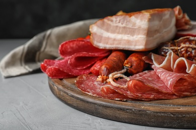 Photo of Cutting board with different meat delicacies on gray table