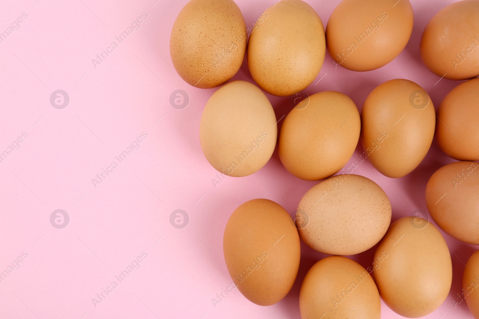 Photo of Raw chicken eggs on pink background, flat lay