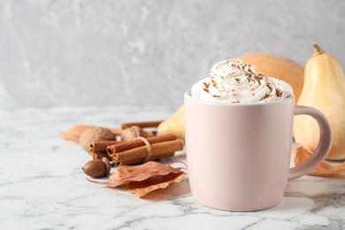 Cup with tasty pumpkin spice latte on white marble table. Space for text