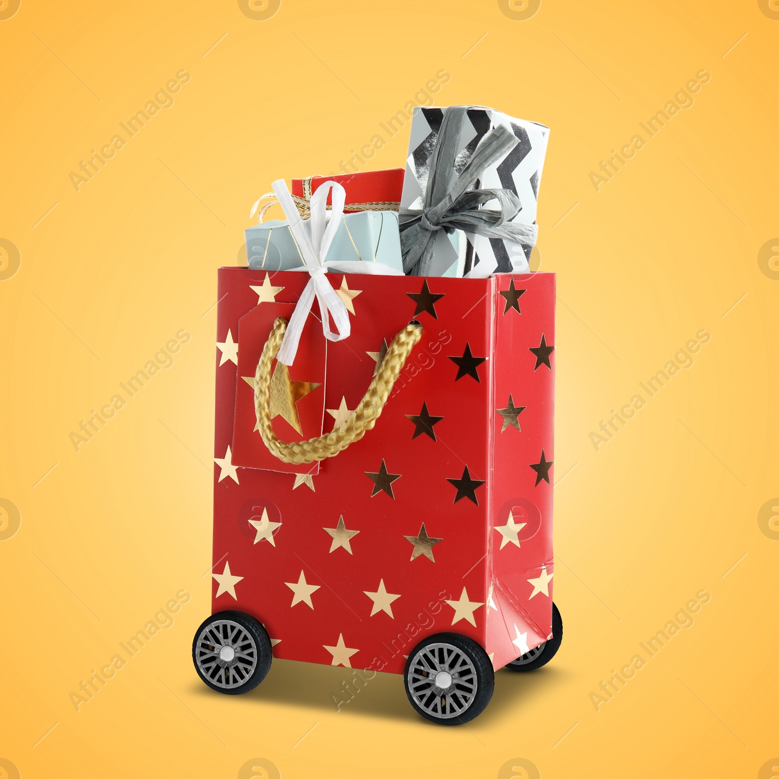 Image of Red shopping bag full of gift boxes on wheels against orange background. Delivery service