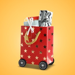 Image of Red shopping bag full of gift boxes on wheels against orange background. Delivery service