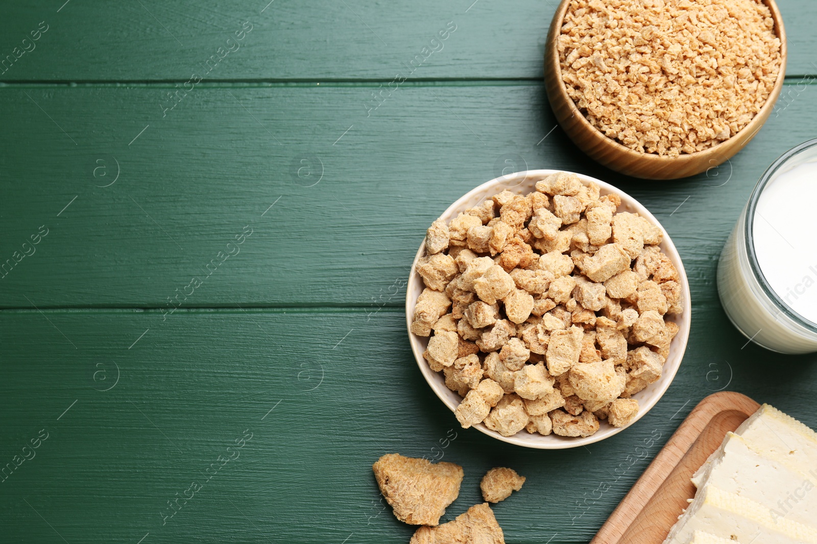 Photo of Different natural soy products on green wooden table, flat lay. Space for text