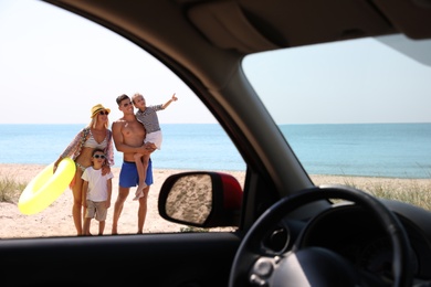 Photo of Happy family with inflatable ring at beach, view from inside of car