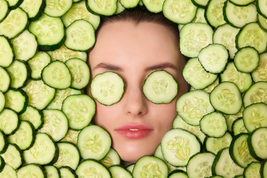 Photo of Beautiful woman among cucumber slices, top view