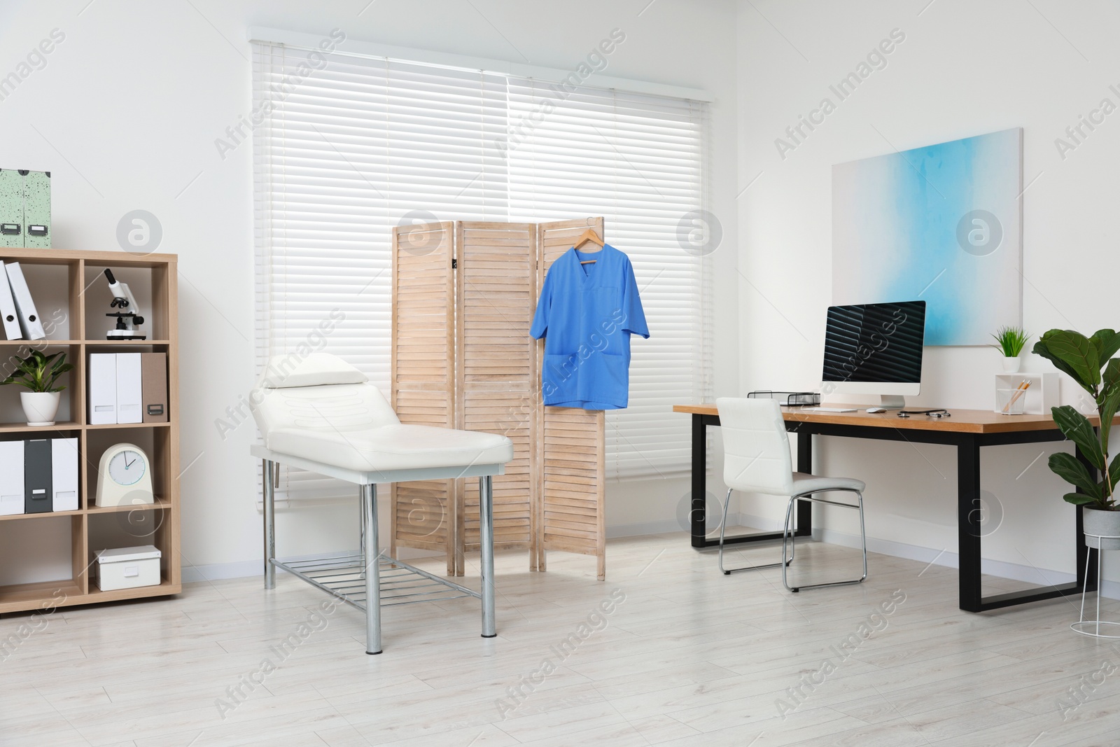 Photo of Modern medical office with doctor's workplace and examination table in clinic