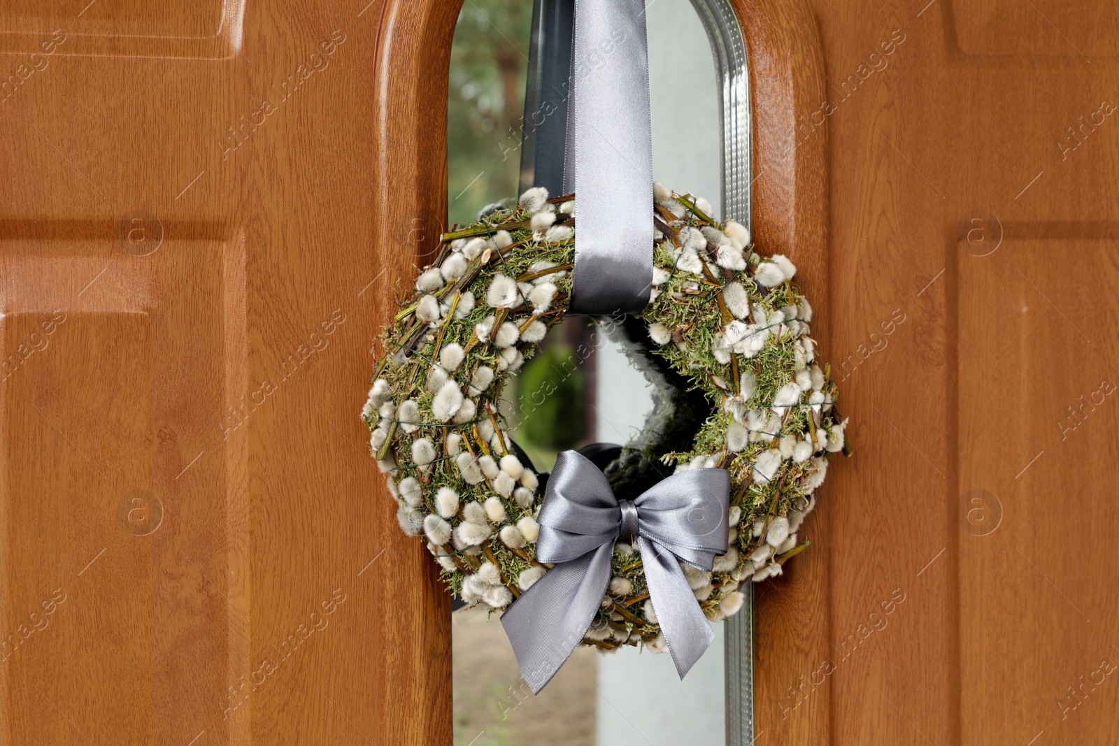 Photo of Wreath made of beautiful willow branches and grey bow on wooden door