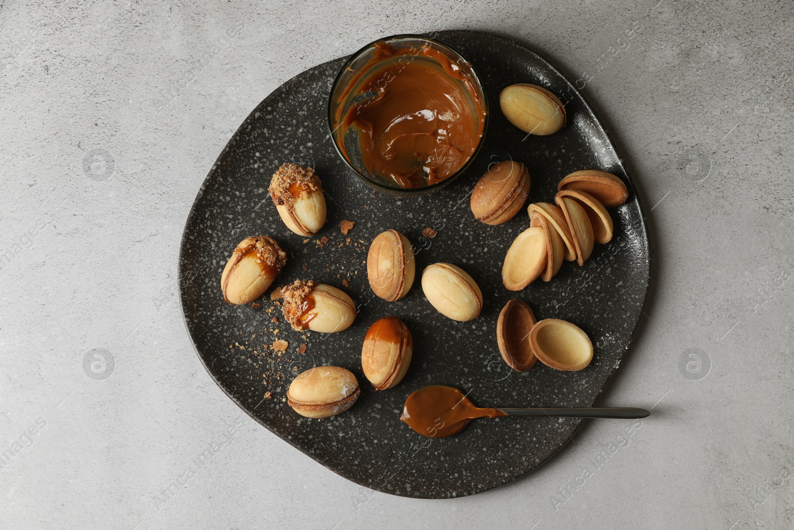 Photo of Delicious walnut shaped cookies with condensed milk on grey table, top view