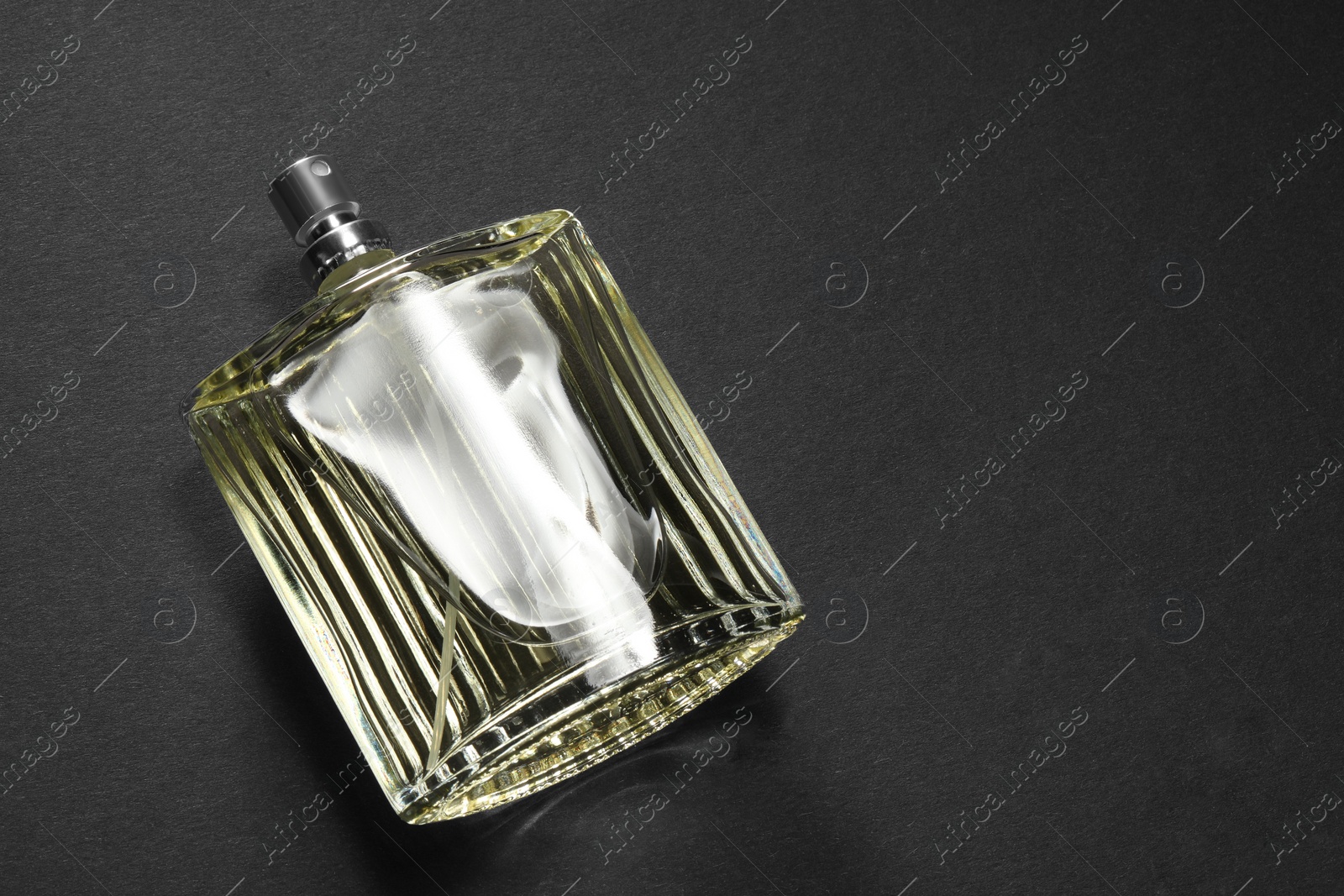 Photo of Luxury men`s perfume in bottle on black background, above view. Space for text