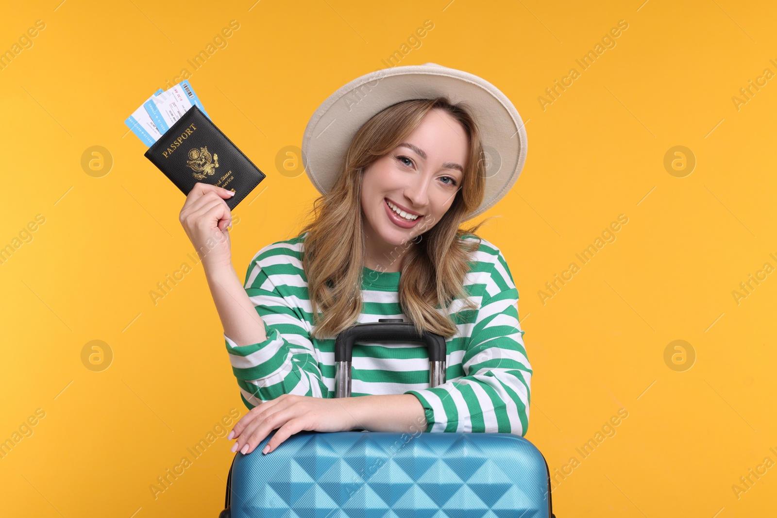 Photo of Happy young woman with passport, ticket and suitcase on yellow background