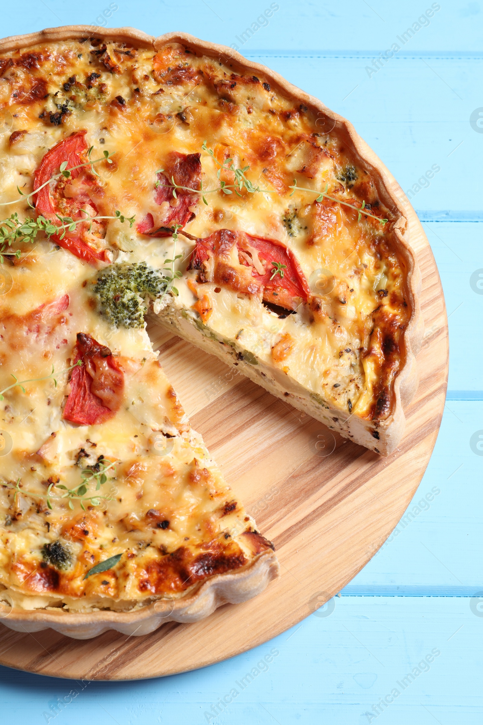 Photo of Tasty quiche with tomatoes, microgreens and cheese on light blue wooden table, above view