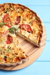 Photo of Tasty quiche with tomatoes, microgreens and cheese on light blue wooden table, above view