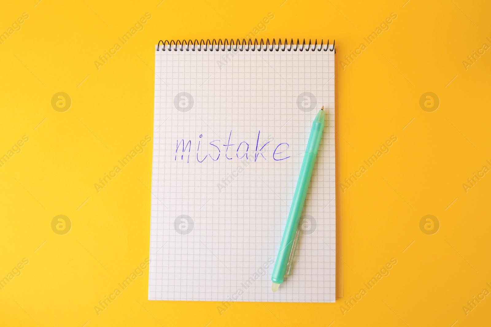 Photo of Word Mistake written with erasable pen in notepad on yellow background, top view