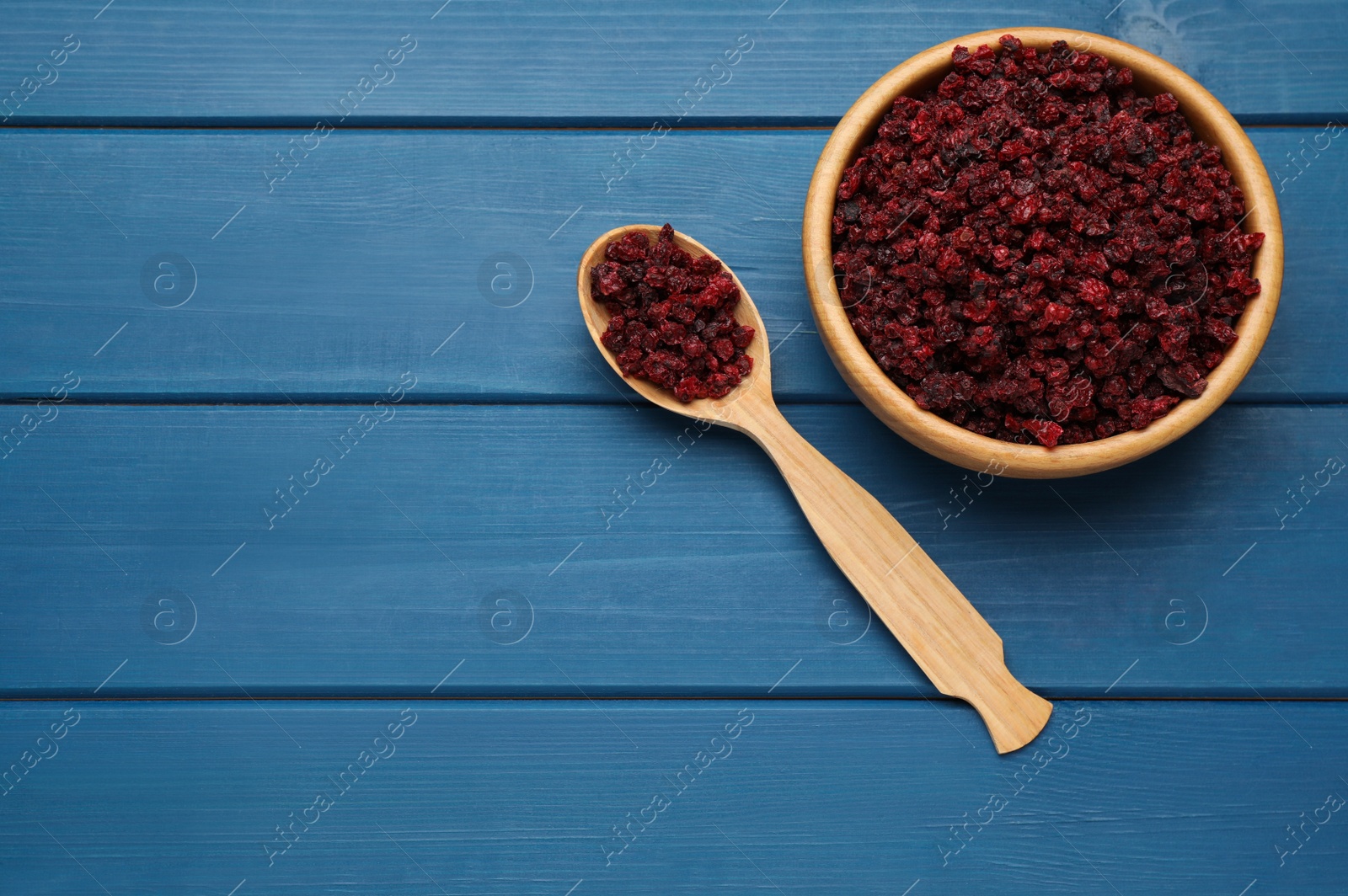 Photo of Dried red currant berries on blue wooden table, flat lay. Space for text