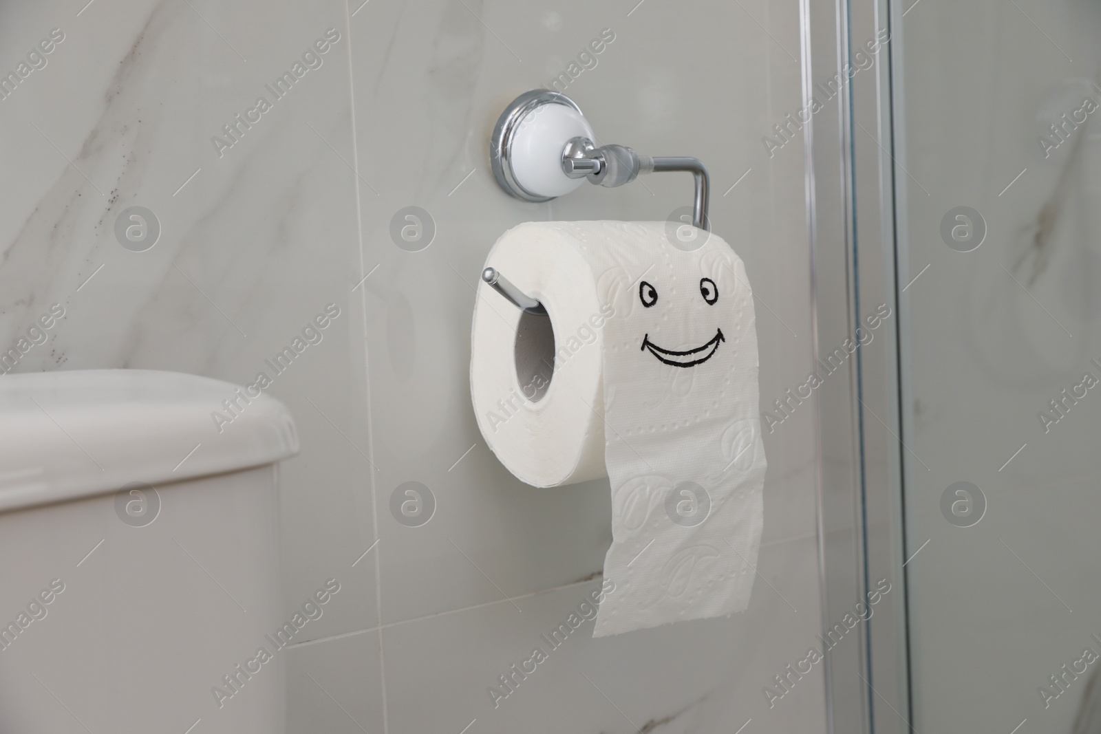 Photo of Paper with drawn funny face near toilet tank in bathroom