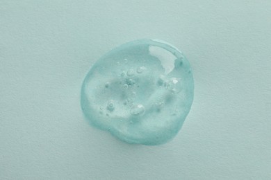 Sample of face gel on light blue background, top view