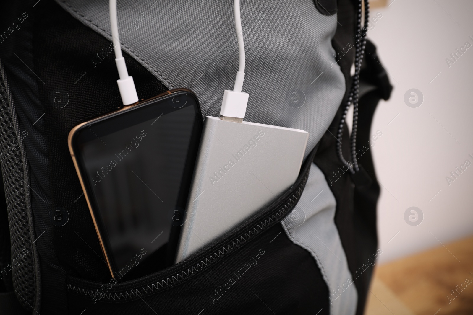 Photo of Smartphone charging with power bank in backpack, closeup