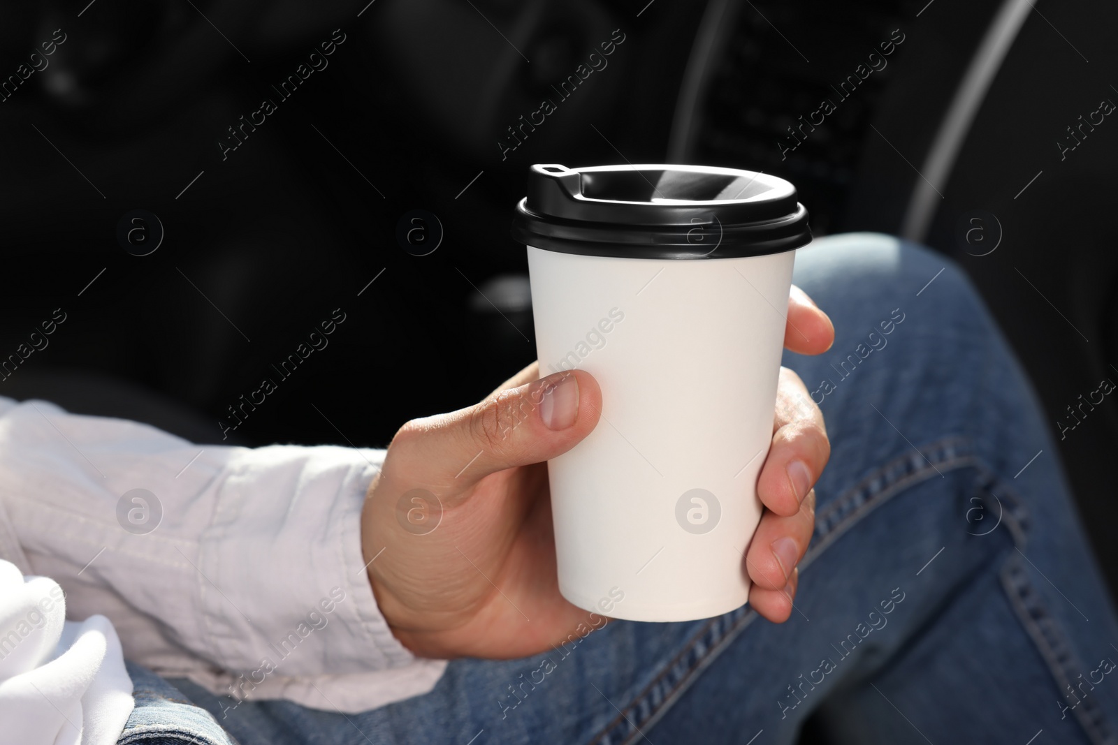 Photo of Coffee to go. Man with paper cup of drink in car, closeup
