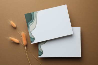 Blank invitation cards and dry plants on beige background, flat lay. Space for text
