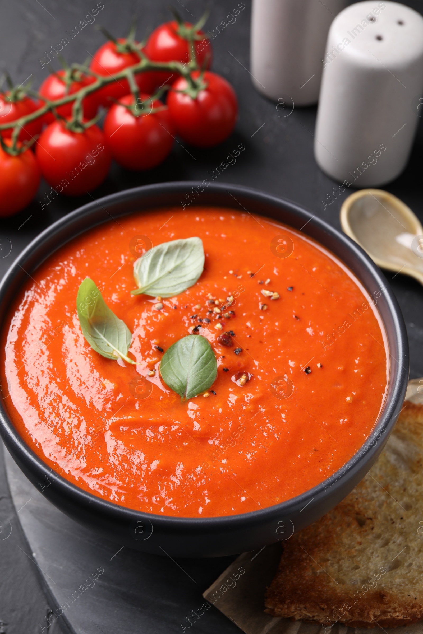 Photo of Delicious tomato cream soup served on black textured table