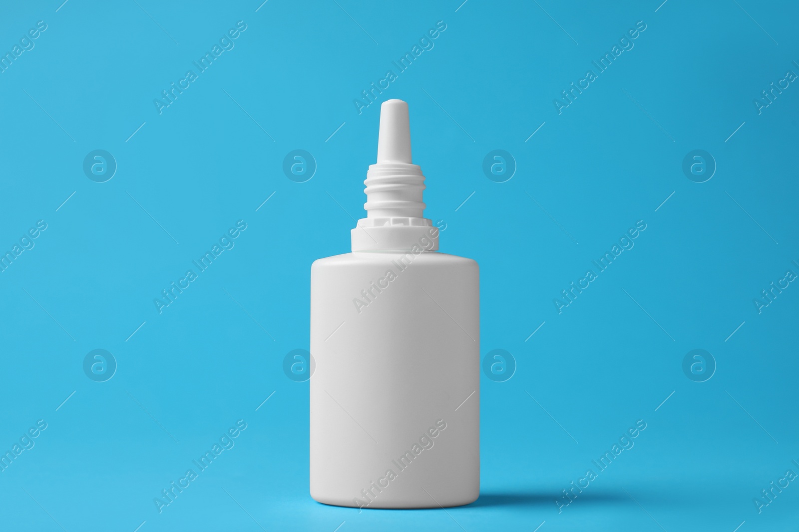 Photo of Bottle of nasal spray on light blue background