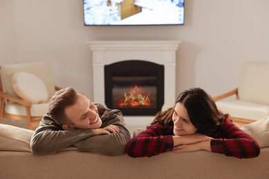 Photo of Happy lovely couple spending time together near fireplace at home