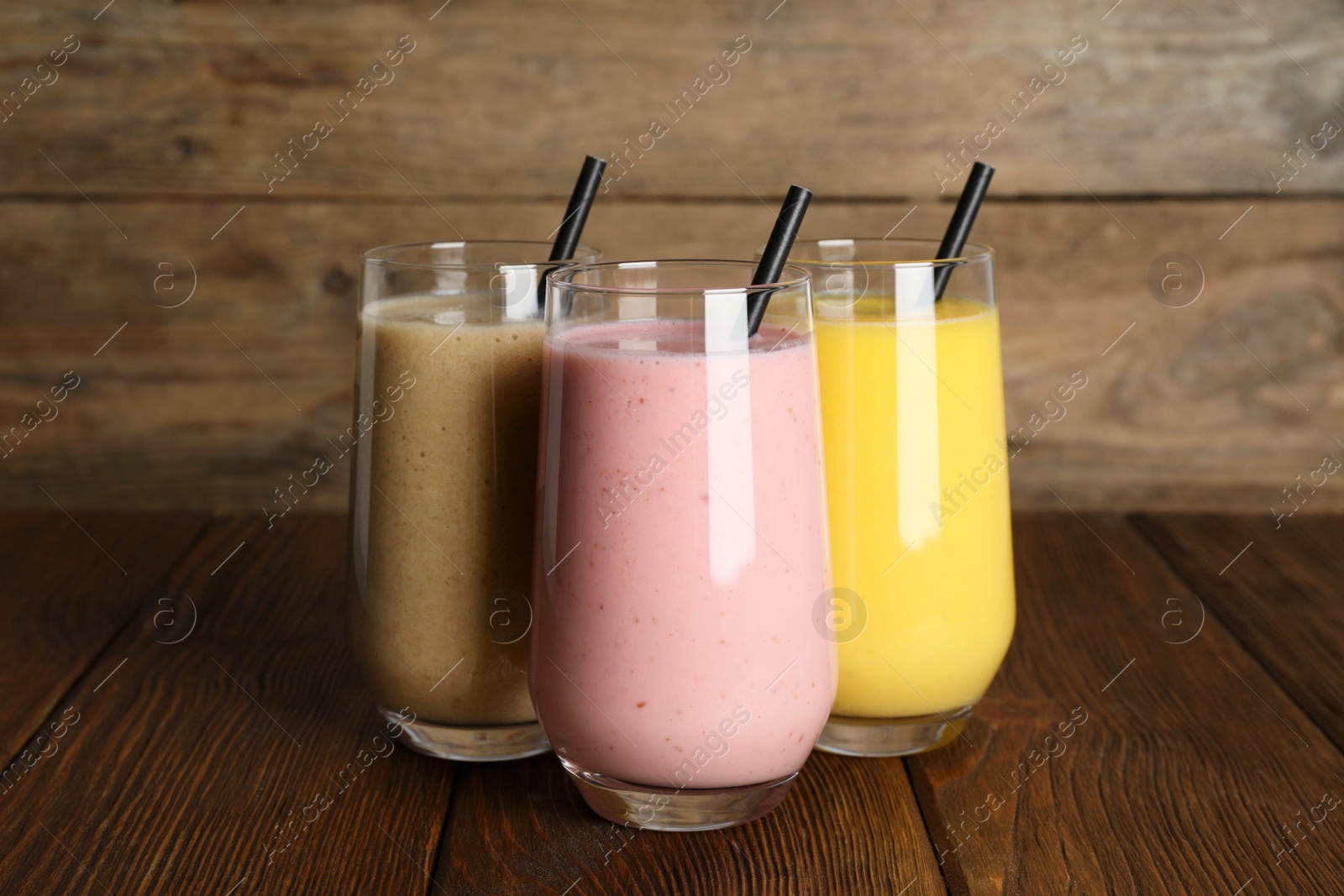 Photo of Glasses with different smoothies on wooden table