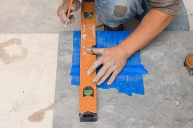 Worker making holes for bathroom water pipes in tile indoors, closeup