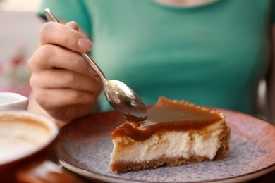 Woman eating slice of cake at table, closeup