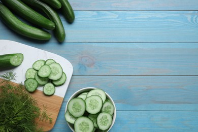 Photo of Fresh ripe cucumbers and dill on light blue wooden table, flat lay. Space for text