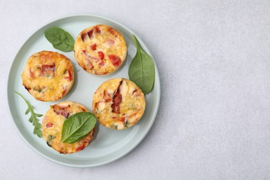Photo of Freshly baked bacon and egg muffins with cheese on light gray table, top view. Space for text