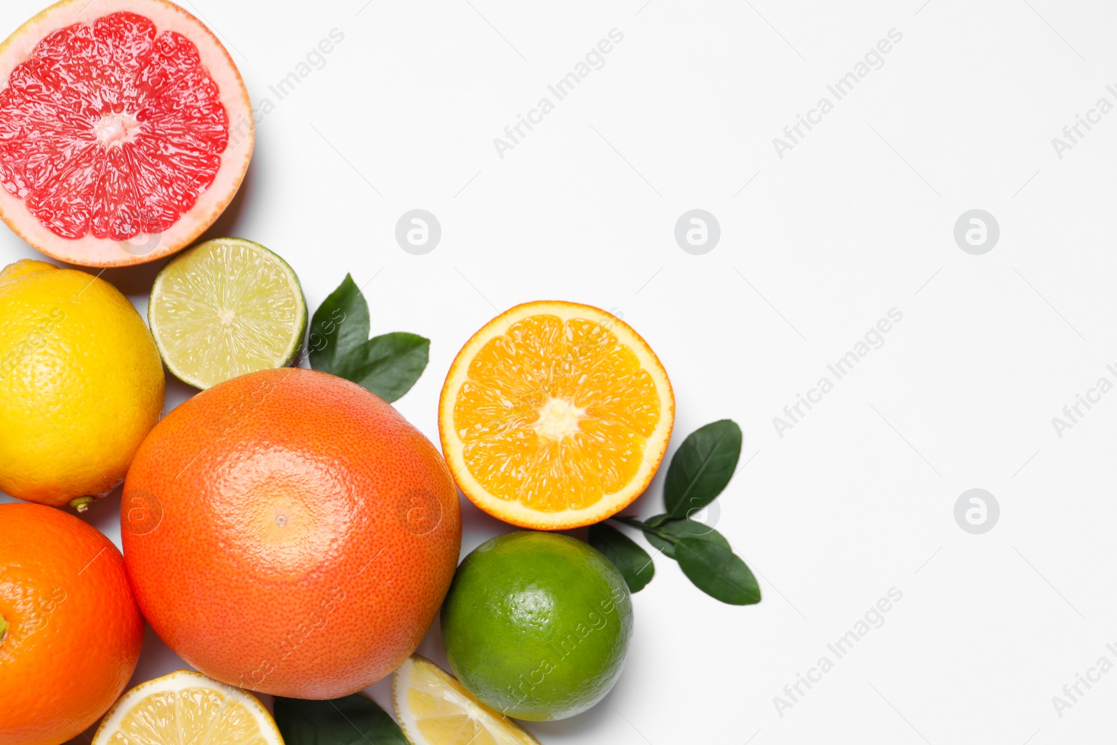 Photo of Different cut and whole citrus fruits on white table, flat lay. Space for text