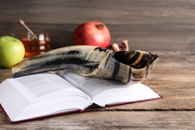 Photo of Shofar and open Torah book on wooden table. Rosh Hashanah holiday attributes