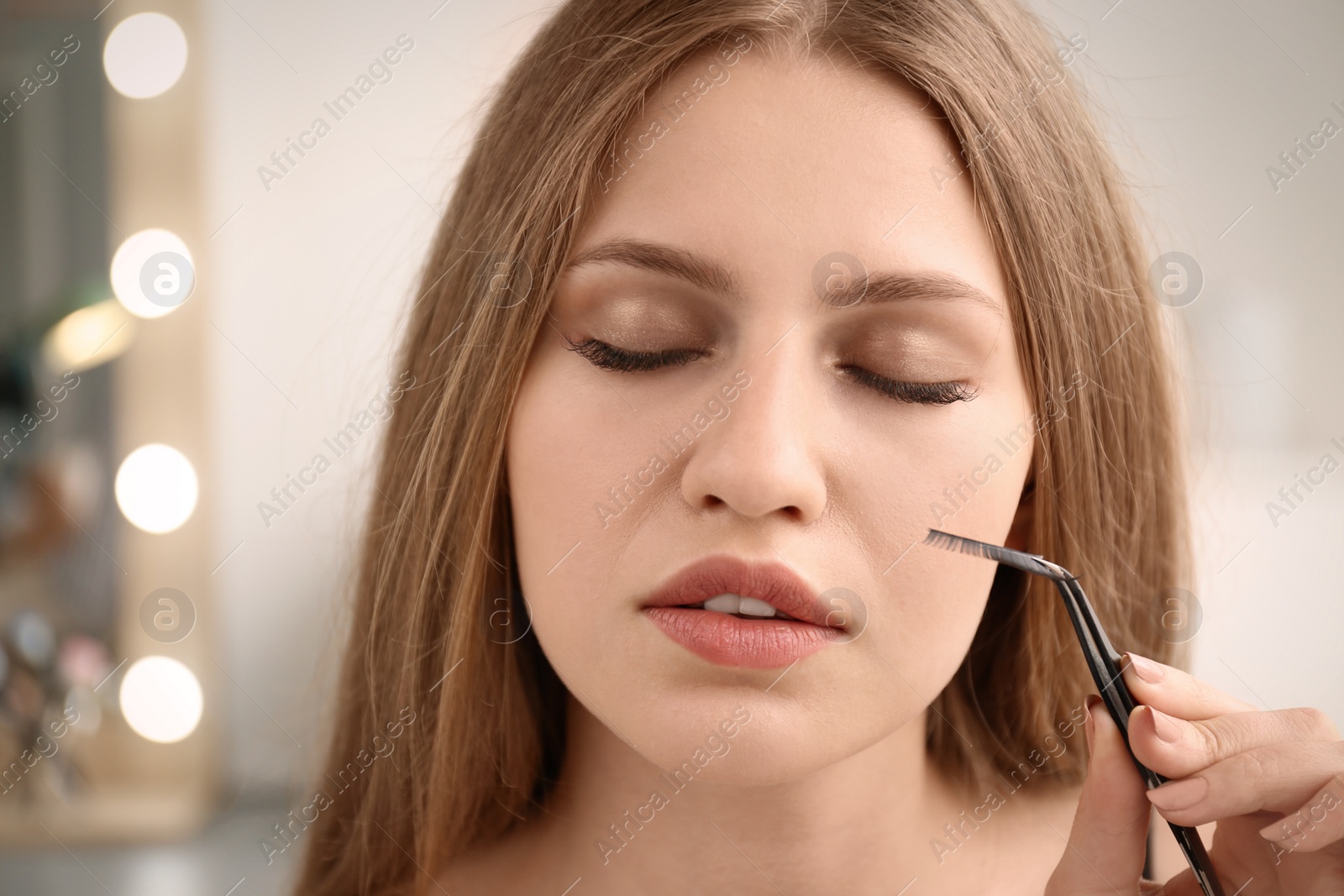 Photo of Attractive young woman with false eyelashes on blurred background