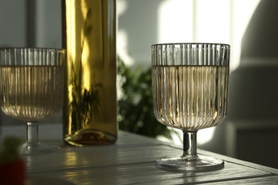 Alcohol drink in glasses and bottle on wooden table indoors, closeup