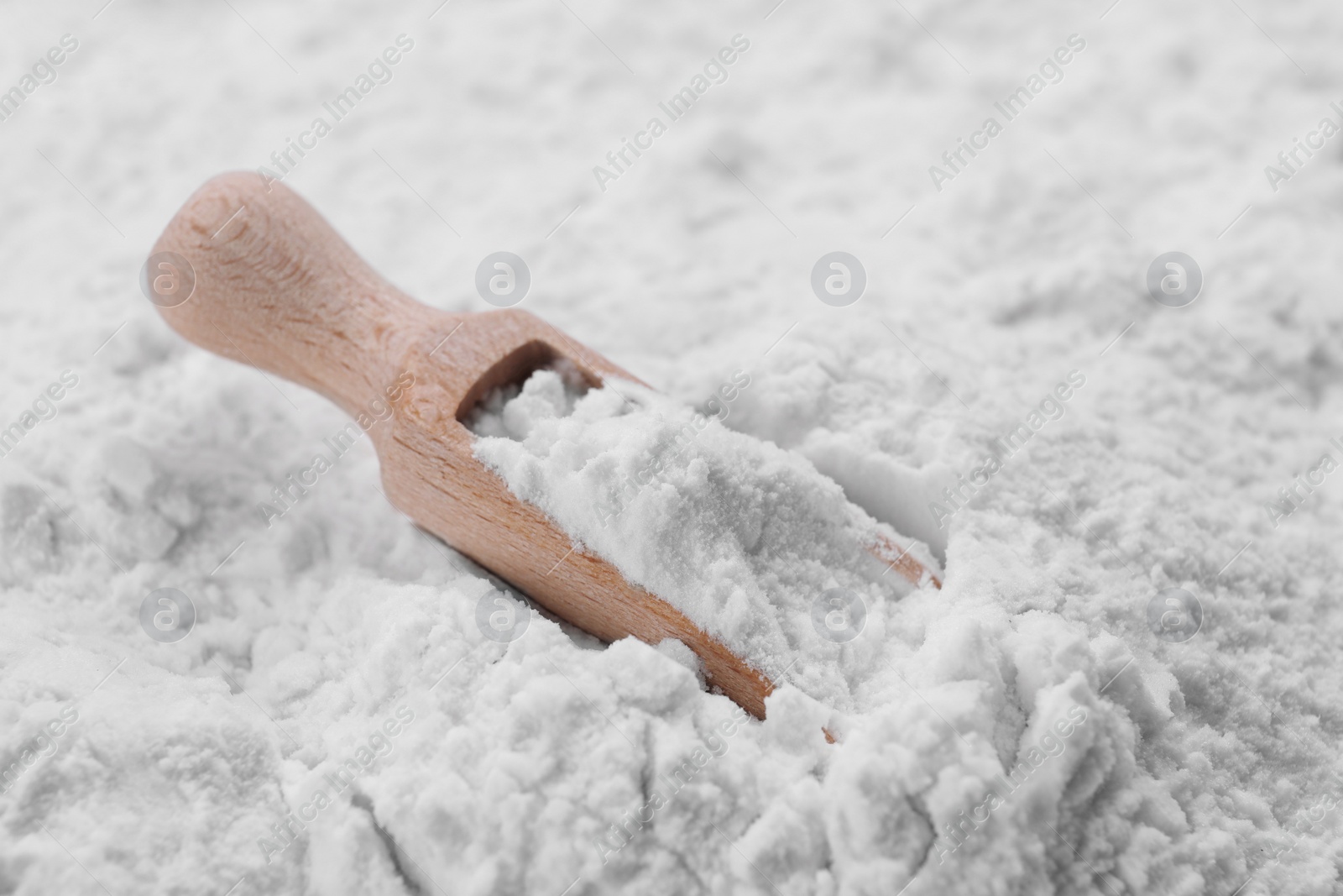 Photo of Heap of natural starch and wooden scoop, closeup