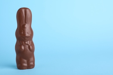 Photo of Chocolate Easter bunny on light blue background, space for text