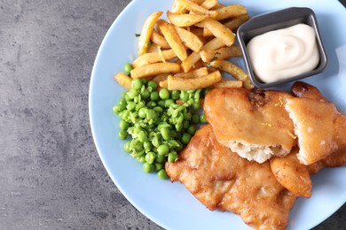 Photo of Tasty fish, chips, sauce and peas on grey table, top view