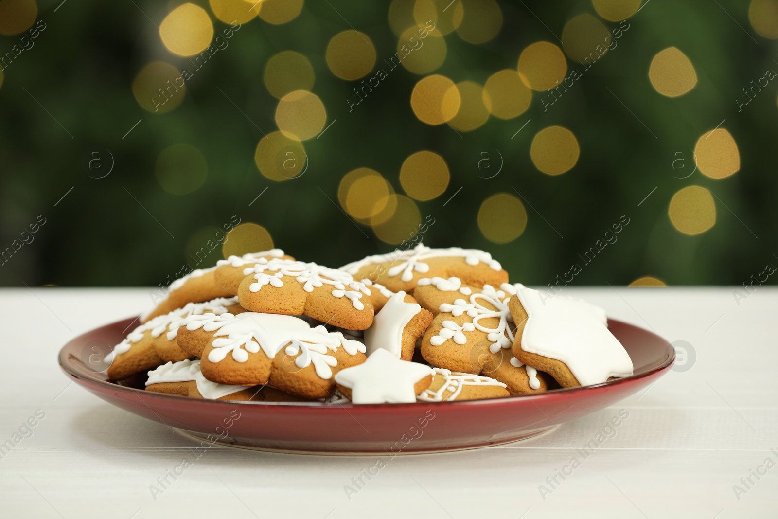 Photo of Decorated cookies on white against blurred Christmas lights