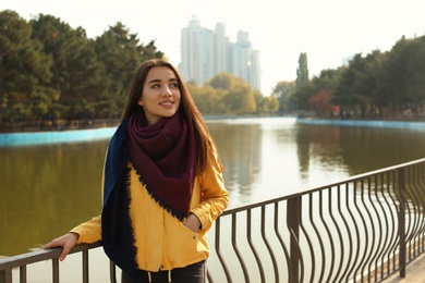 Photo of Young beautiful woman near pond in park. Autumn walk