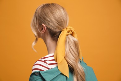 Photo of Young woman with stylish bandana on yellow background, back view