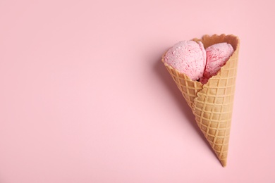 Photo of Delicious ice cream in wafer cone on pink background, top view. Space for text